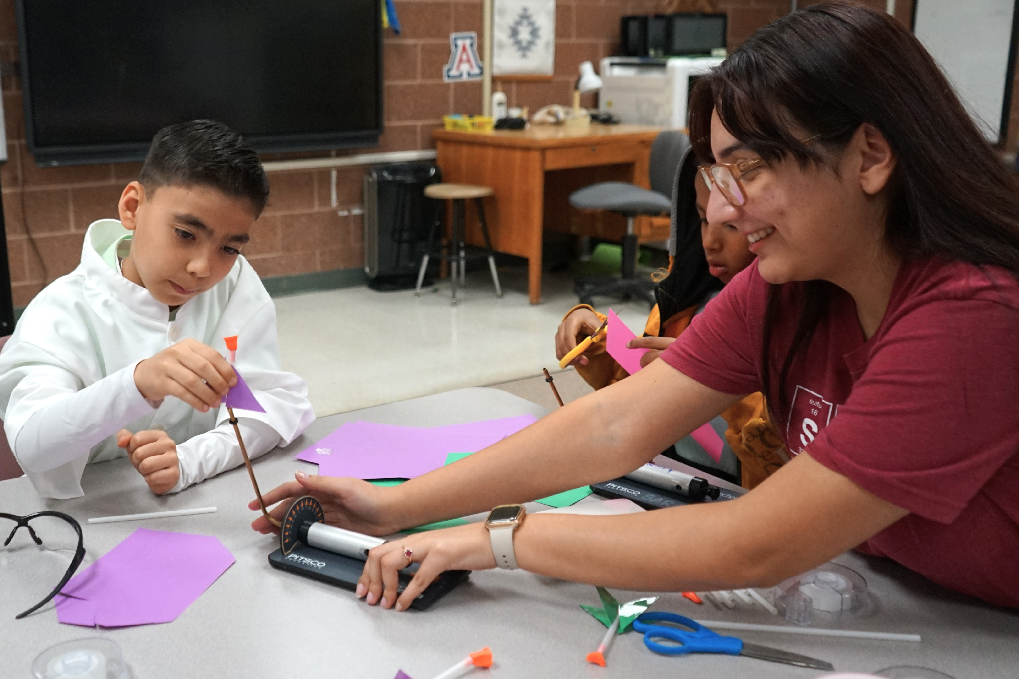 A woman demonstrates a STEM toy for a little boy to play with