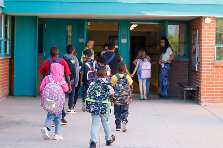 Students walk into school wearing their backpacks