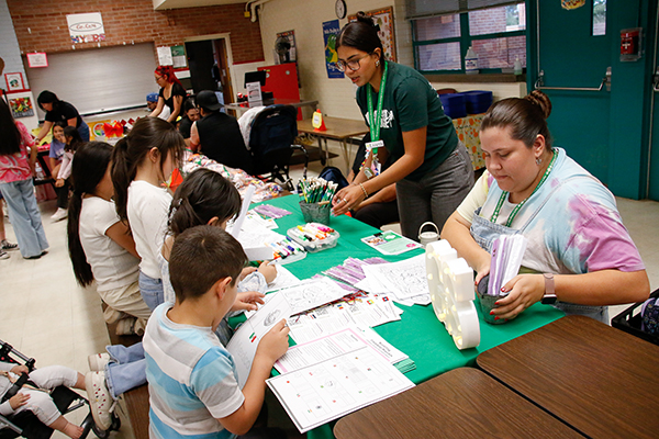Students work on a craft project at a cafeteria table