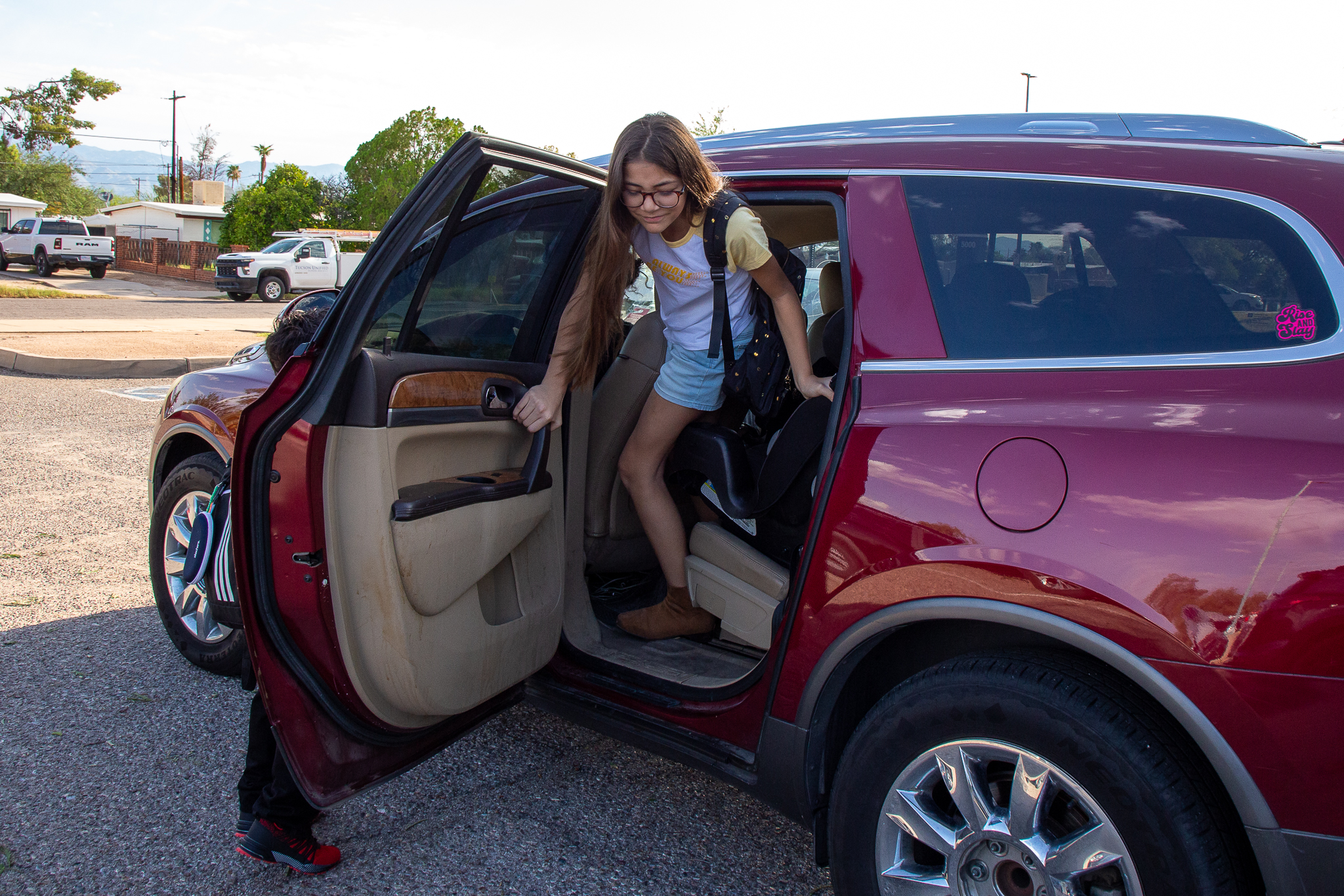 A girl gets out of her family's red SUV on the first day