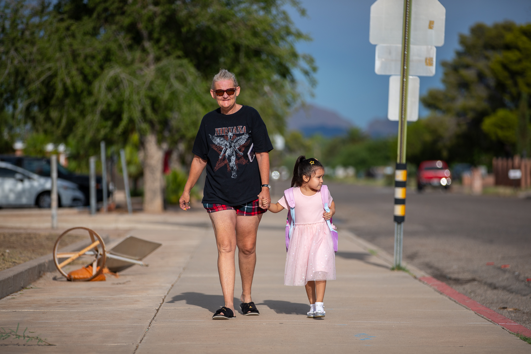 A woman walks with her young granddaughter into school