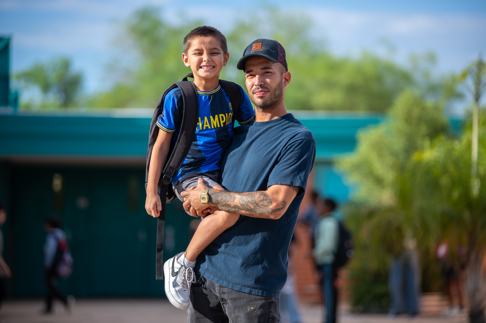 A dad holds up his smiling young son on the first day