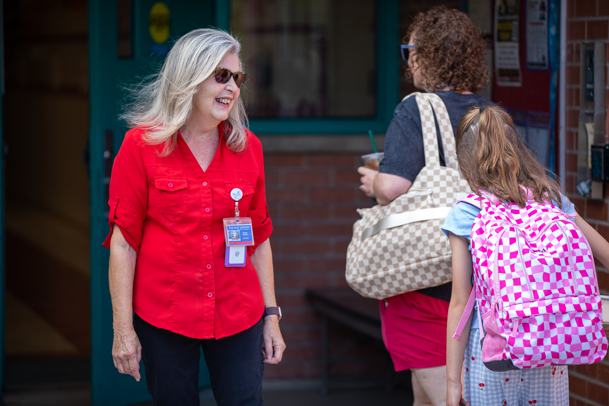 A woman greets a mom and daughter as they walk in