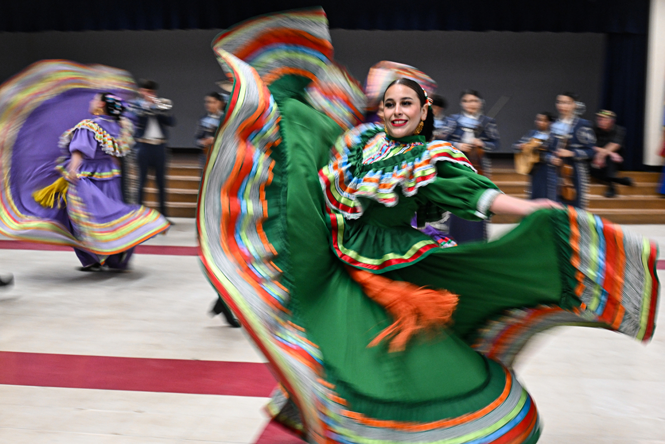 A teen girl performs folklorico in a traditional dress.